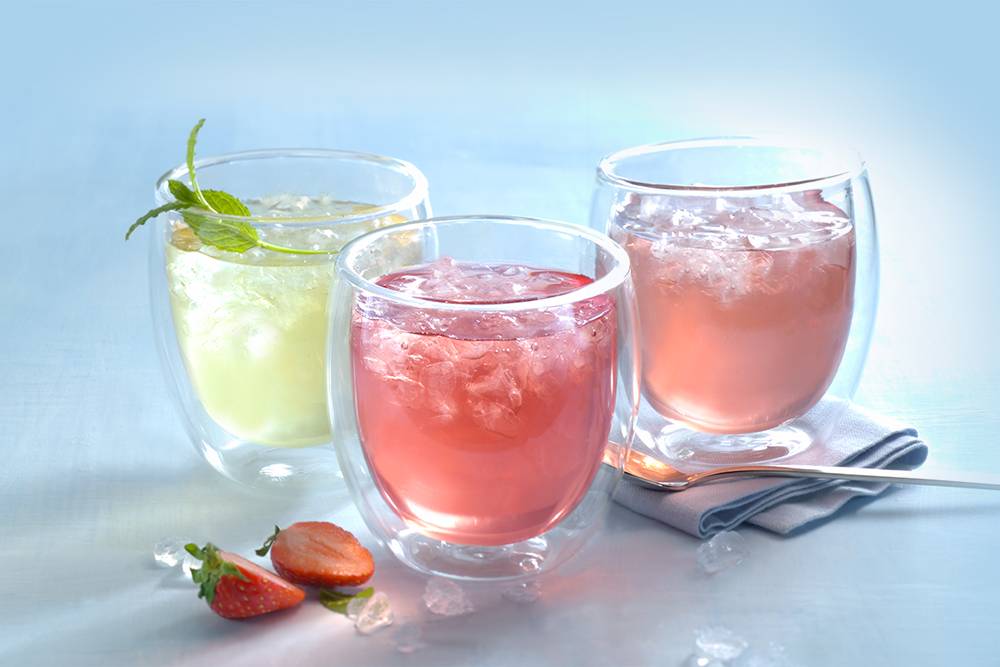 3 Thermoteegläser mit verschiedenfarbigen Eistees und Eiswürfeln
