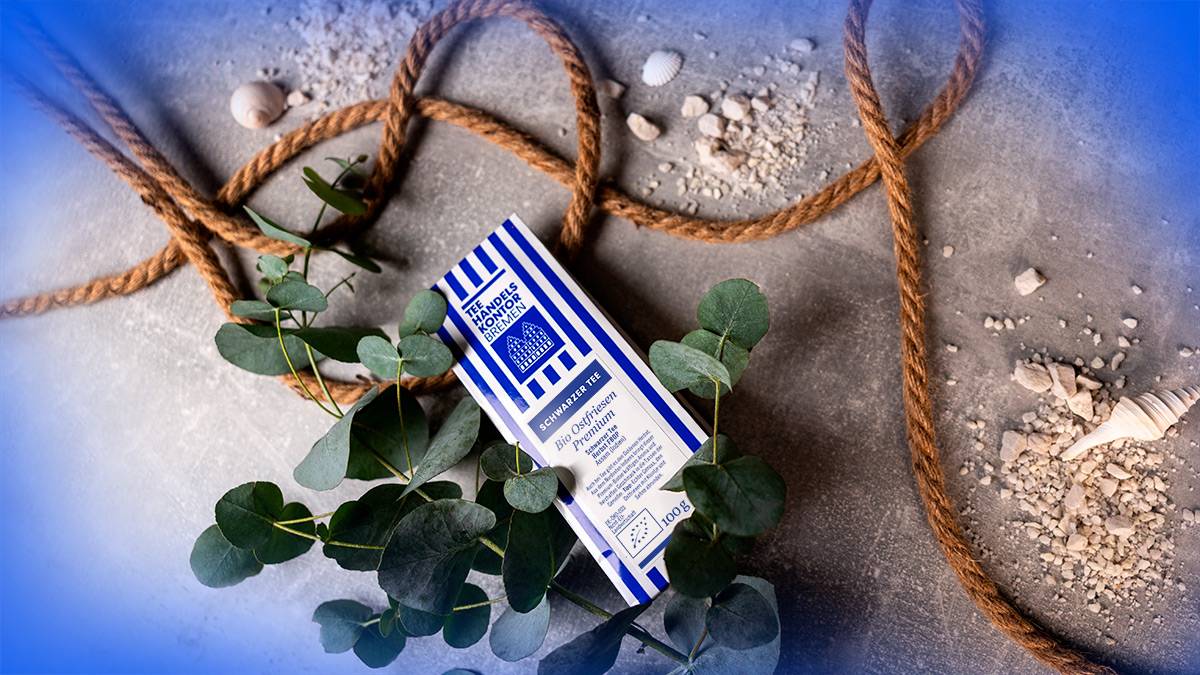 Auf blauem, maritim dekoriertem untergrund liegt eine Tüte mit losem Schwarztee