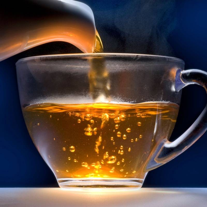 Dekoratives Bild mit aufgebrühtem Schwarztee Darjeeling Gold Star in einer Glastasse